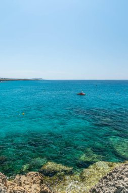 CYPRUS, NISSI BEACH - MAY 12/2018: Tourists swim on catamarans and kayaks in the popular bay of the Mediterranean Sea.