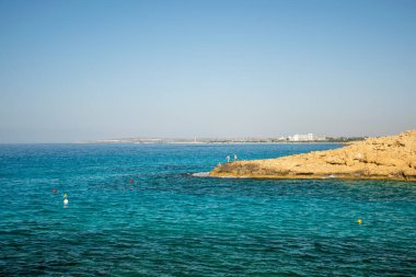 Balıkçılar gök mavisi denizin kayalık sahillerinde balık tutarlar..