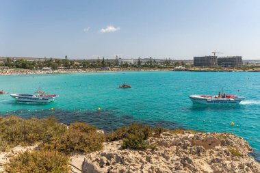 CYPRUS, NISSI BEACH - MAY 12/2018: Tourists swim on catamarans and kayaks in the popular bay of the Mediterranean Sea.