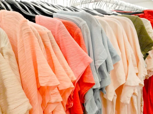 Coloridas camisetas colgadas en la tienda de ropa —  Fotos de Stock