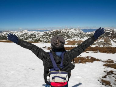 Gezgin Shika karlı dağında kollarını kaldırıyor.