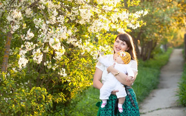 En el jardín de primavera con flor de cerezo mamá y bebé hija disfrutar de la naturaleza —  Fotos de Stock