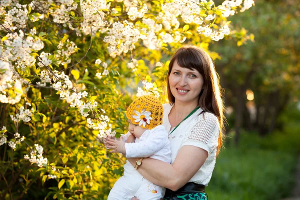 Nel giardino primaverile con fioritura ciliegia mamma e figlia bambino godersi la natura — Foto Stock