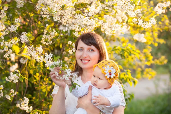 En el jardín de primavera con flor de cerezo mamá y bebé hija disfrutar de la naturaleza —  Fotos de Stock