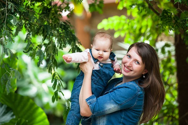 Joyeux jeune femme tenant un bébé sur une promenade dans le Par — Photo