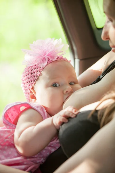 Una mujer alimenta a su bebé en el coche —  Fotos de Stock