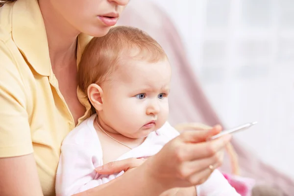 Une jeune femme pour mesurer la température d'un enfant — Photo