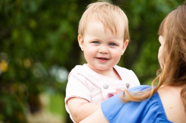 Yeşil zemin üzerine genç bir kadının kollarında çocuk