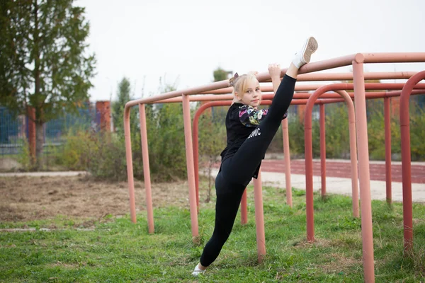 Tienermeisje sport in het stadion voert gymnastische oefeningen — Stockfoto
