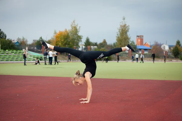 Tienermeisje sport in het stadion voert gymnastische oefeningen — Stockfoto