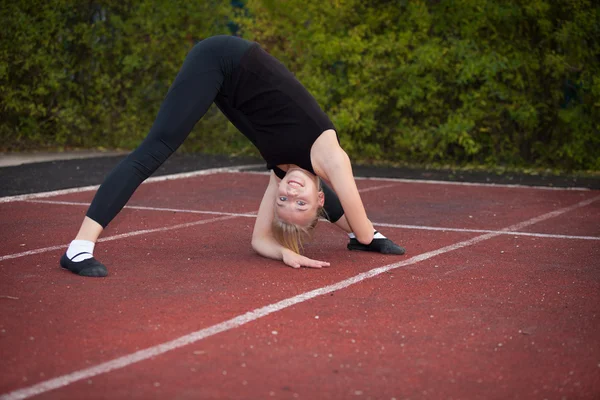 Sport tizenéves lány a stadionban hajt végre gimnasztikai gyakorlatok — Stock Fotó