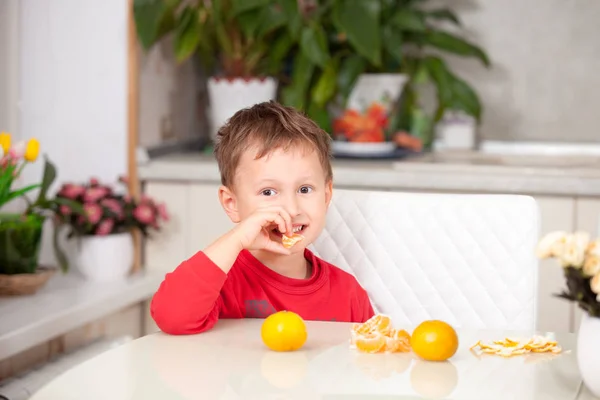 Felice ragazzo pulisce mandarini — Foto Stock