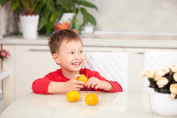 Felice ragazzo pulisce mandarini — Foto Stock