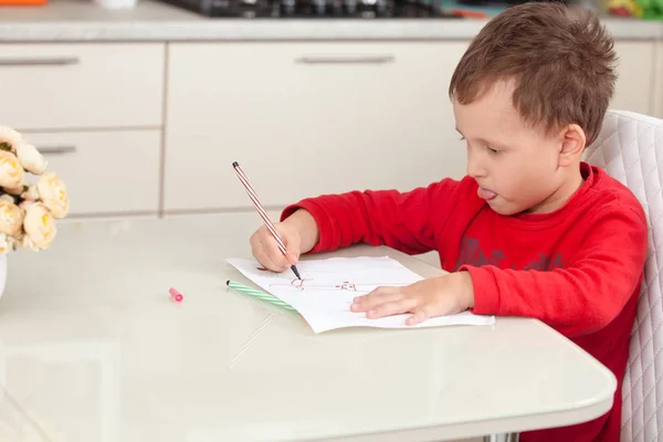 Inspired by the boy draws a picture on the paper at the table — Stock Photo, Image