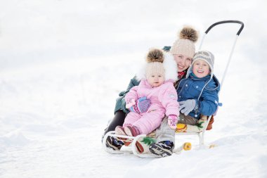 Kış bir kızak üzerinde iki çocuklu mutlu genç kadınla yürümek