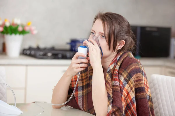 Jonge vrouw inhaleren met een vernevelaar thuis doen — Stockfoto