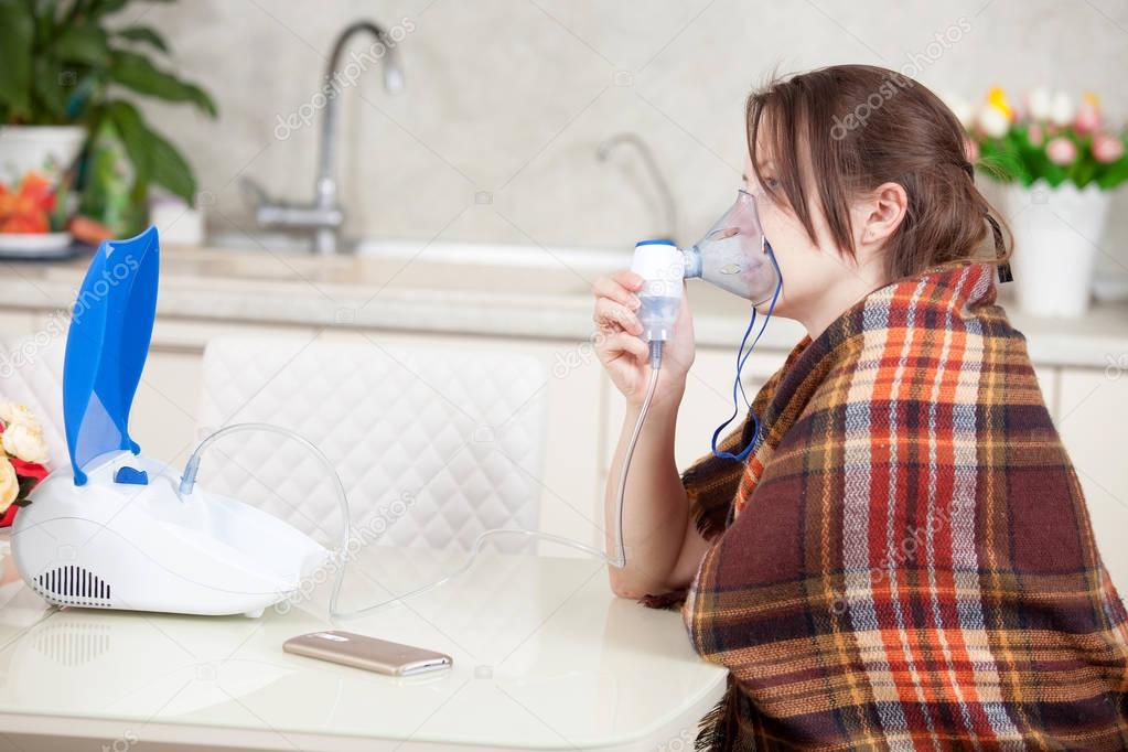 Young woman doing inhalation with a nebulizer at home