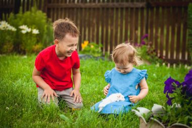 Mutlu çocuklar bir yeşil kobay ile oynarken bahçede çim çimen.