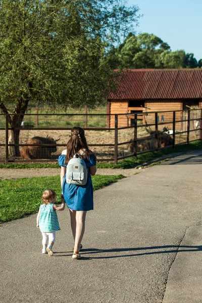 Una joven con una niña caminando por el zoológico. Madre e hija . —  Fotos de Stock