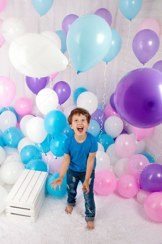 Hilarious boy with bunch of colorful balloons. Playing with balloons. Isolated on white.
