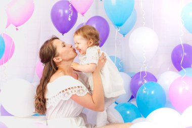 Mutlu anne kızı renkli balonlar göl kenarında beyaz bir sürü sarılma.