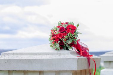 Buket düğün. Gelin buketi. Bir buket kırmızı ve pembe Gül, çilek ve yeşil, kırmızı, bir şerit ile gökyüzü bir arka plan üzerinde yatıyor