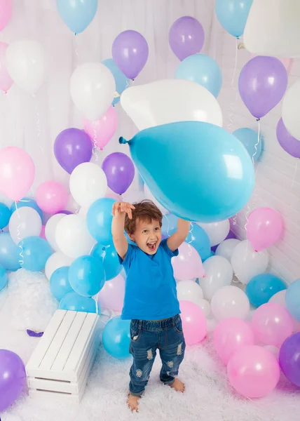 Chico hilarante con un montón de globos de colores. Jugando con globos. Aislado sobre blanco . —  Fotos de Stock