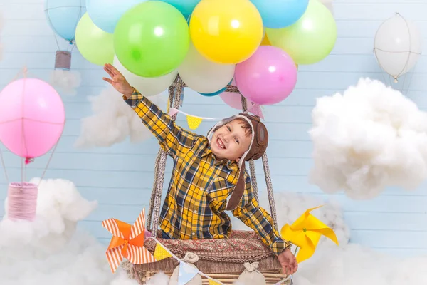 Ein kleines Mädchen sitzt in einem Heißluftballonkorb im Park und tut so, als würde es reisen und mit Pilotenhut fliegen, um ein kreatives oder phantasievolles Konzept zu entwickeln. — Stockfoto