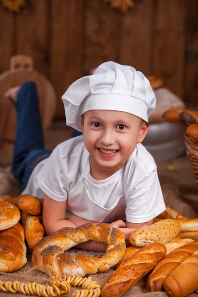 Kucharz dziecko ubrane leży Baker dużo chleb bułki — Zdjęcie stockowe