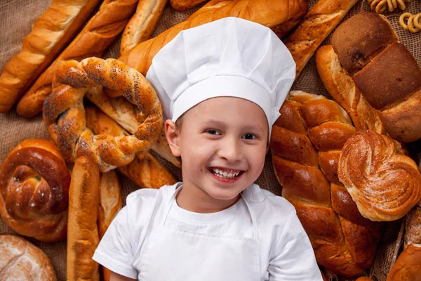 Bebê cozinheiro vestido mentira Baker um monte de pães — Fotografia de Stock