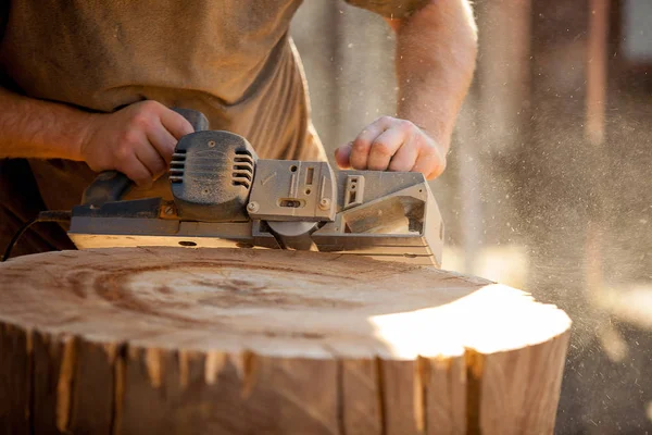 Плотник, работающий с электроагрегатом на деревянных пнях на открытом воздухе — стоковое фото