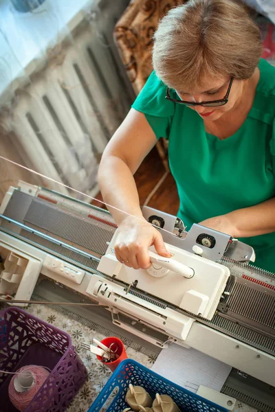 Женщина вяжет на вязальной машине, работает руками — стоковое фото