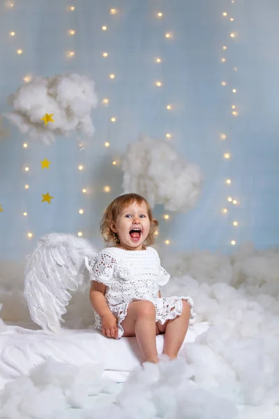 Söt liten ängel sitter i molnen skrattar glatt — Stockfoto