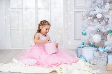 Koridorda büyük beyaz bir Noel ağacı olan bir çocuk.