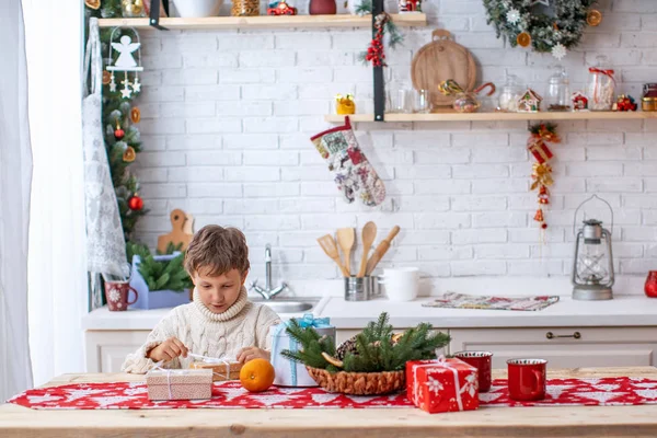 Gelukkige jongen op keukentafel met geschenkdozen — Stockfoto