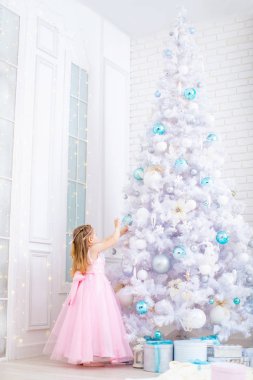 Bir çocuk Noel ağacını oyuncaklarla süslüyor.