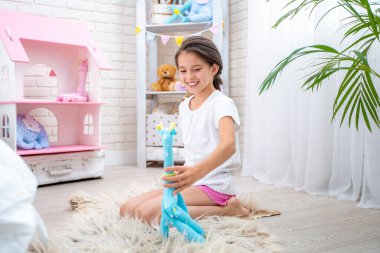 Açık pijama giymiş, kumaştan bir oyuncakla, zürafayla çocuklarının odasında oynayan mutlu şirin bir kız. Oda ışık ve oyuncaklarla dolu. Sevimli kız mutlu ve dikkatsizce gülümsüyor ve oynuyor.