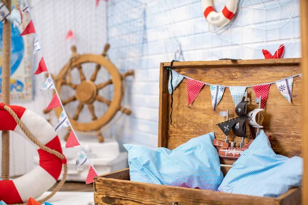 Decoration of the room in a pirate style, with a helm and a treasure chest. for a photo shoot and a pirate party. balls in honor of the birthday. Marine decor from textiles