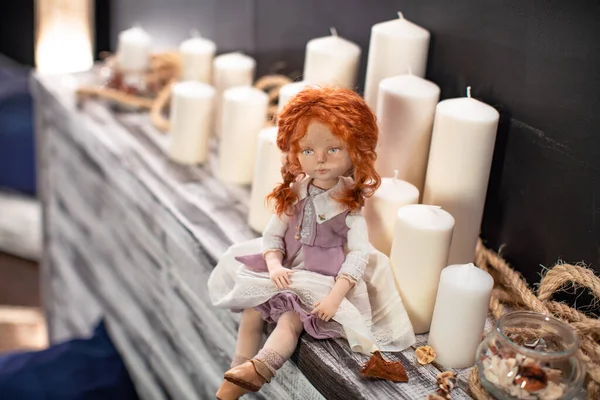 用纺织品手工制作的内饰娃娃 复古风格 一个有人脸的设计师娃娃 坐在桌子上 桌子上放着巨大的内插蜡烛 为假期创造洋娃娃 独家新闻 — 图库照片