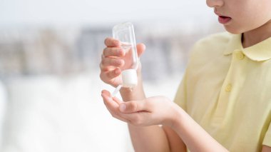 Covid-19 Coronavirüs kavramı. Küçük çocuk virüsten korunmak için ve halka açık alandaki salgını önlemek için alkol jel dezenfektanı ile ellerini temizliyor. Salgın bir virüsün belirtisi..