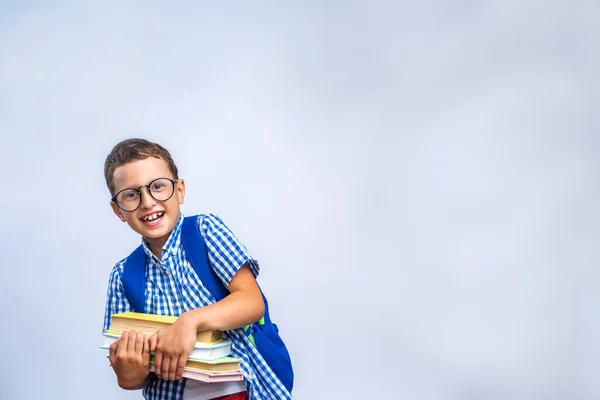 学校に戻る 眼鏡をかけて面白い小さな男の子は 単に薄い灰色の背景に笑っている 本と袋を持った小学生の子供 コピースペース — ストック写真