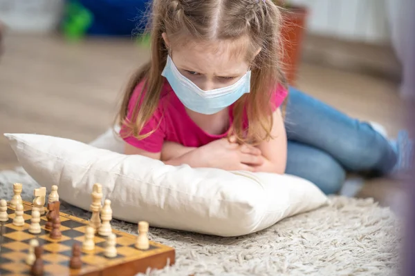 Gyerek Orvosi Maszkkal Arcán Sakkozik Földön Fekszik Lány Ideges Mert — Stock Fotó