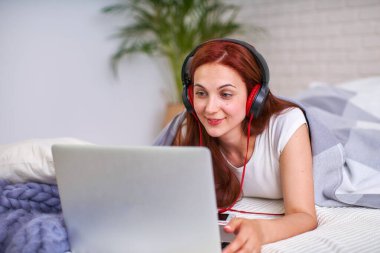 Kız öğrenci arkadaşlarıyla internet üzerinden iletişim kurmaktan mutlu. Evde eğitim, iş ve öğrenim, yeni bilgi. Yatakta bilgisayarla mutlu bir genç. Kadınlar yatakta dizüstü bilgisayara bakıp gülümsüyor..