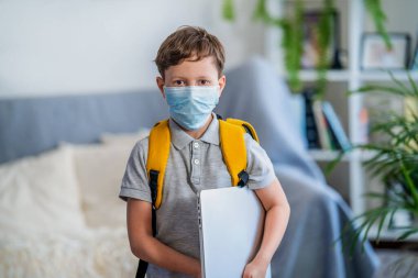 Corona virüsü ve grip salgını sırasında maske takan küçük okul çocuğu. Çocuklar için hastalık koruması. Koronavirüsü önleme maskesi. Okul çocuğu öksürüyor. Küçük çocuk maskeyle nefes alıyor, okula gidiyor..