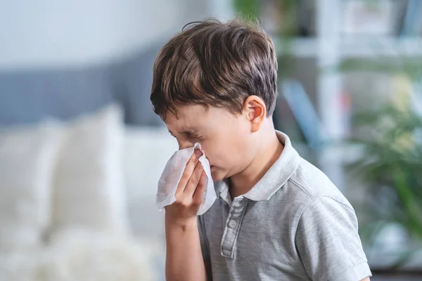 Sick ?aucasian boy blowing nose into tissue, Unhealthy child suffering from running nose or sneezing and covering his nose and mouth by tissue paper. period of the flu and SARS epidemic