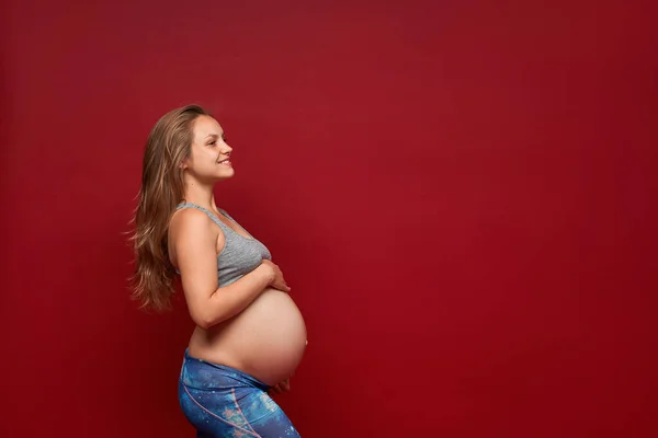 Slim Pregnant Girl Sportswear Embracing Belly Smiling Looking Aside Red — Stock Photo, Image