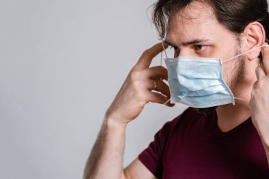 Tehlikeli virüse karşı korunmak için tıbbi maske takıyor. COVID-19, SARS, NCov-19 'a karşı koruyucu önlem olarak tıbbi koruyucu maske takan kendinden emin adam.