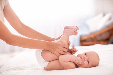 Bebek masajı. Masör, kolik sırasında bebeğin karnına masaj yapıyor. Bebek bezli yeni doğmuş bir bebek sırt üstü uzanıyor ve sancılarla başa çıkmasına yardım ediyor. Bacaklarını karnına bastırıyor..
