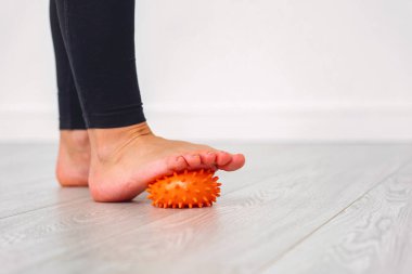 Spor giyim bölümünde bir bacağa masaj topu yakın plan. Topa ayak bastır. Evde antrenman. Ayak hastalıklarının önlenmesi. Sağlıklı yaşam tarzı ve spor kavramı.