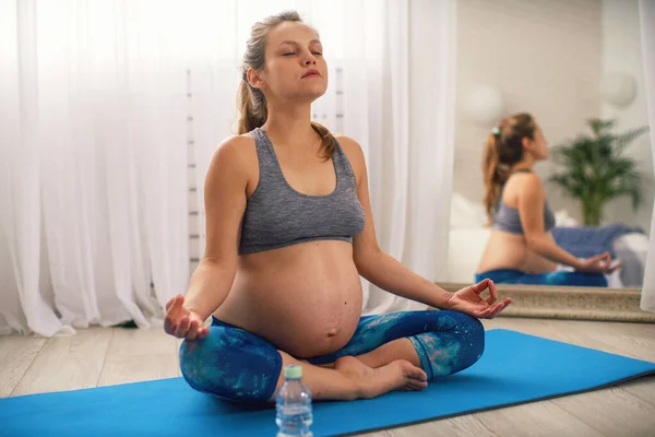 healthy mind and spirit. Beautiful expectant mother does yoga. A pregnant woman in sports clothes, relaxed and meditating in the Lotus position. Copy space.